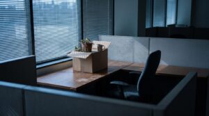 Empty office cubicle at dusk with a cardboard box of personal belongings on the desk