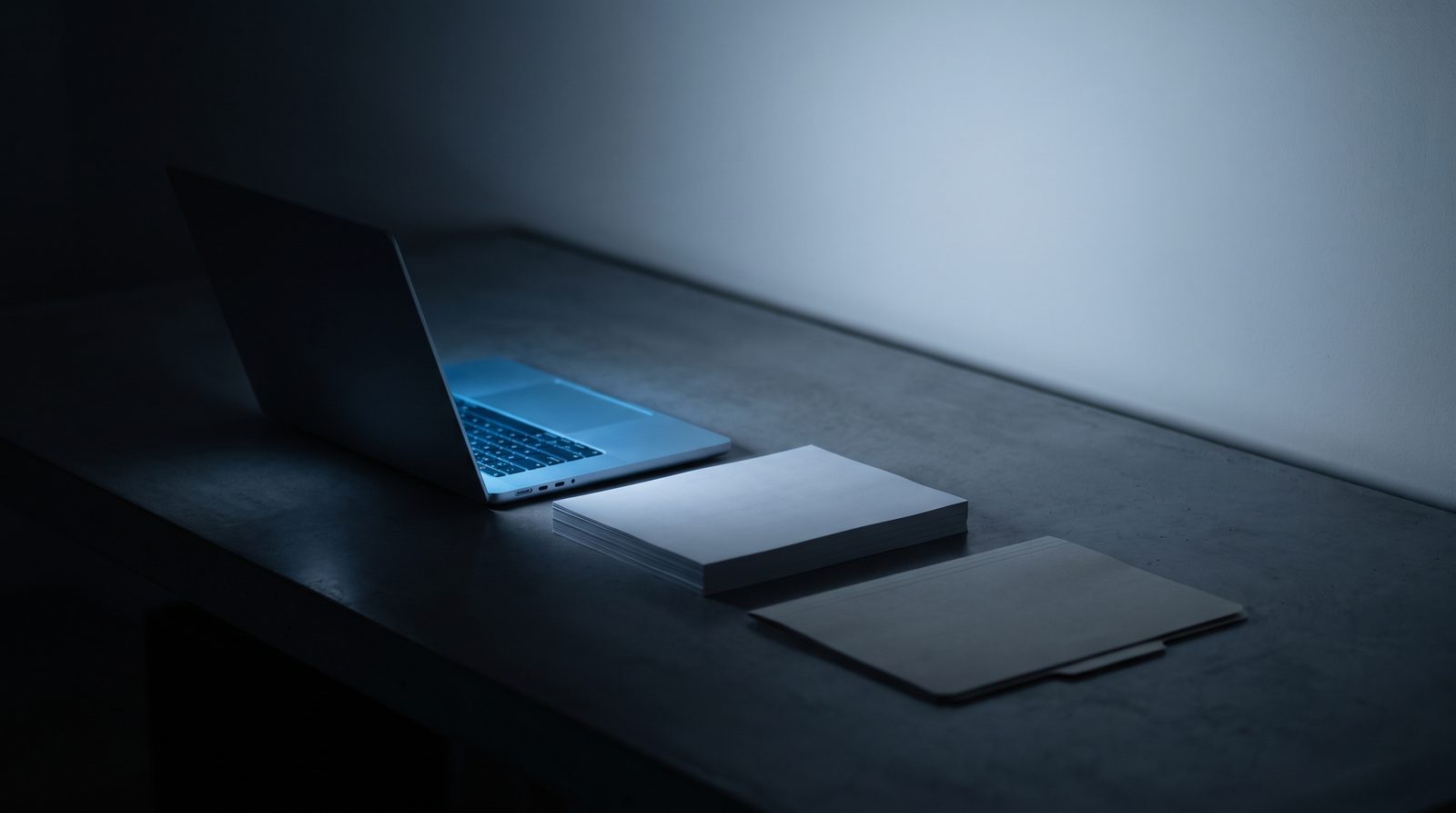 Laptop and a neat stack of printed documents beside a folder, representing a work documents paper trail